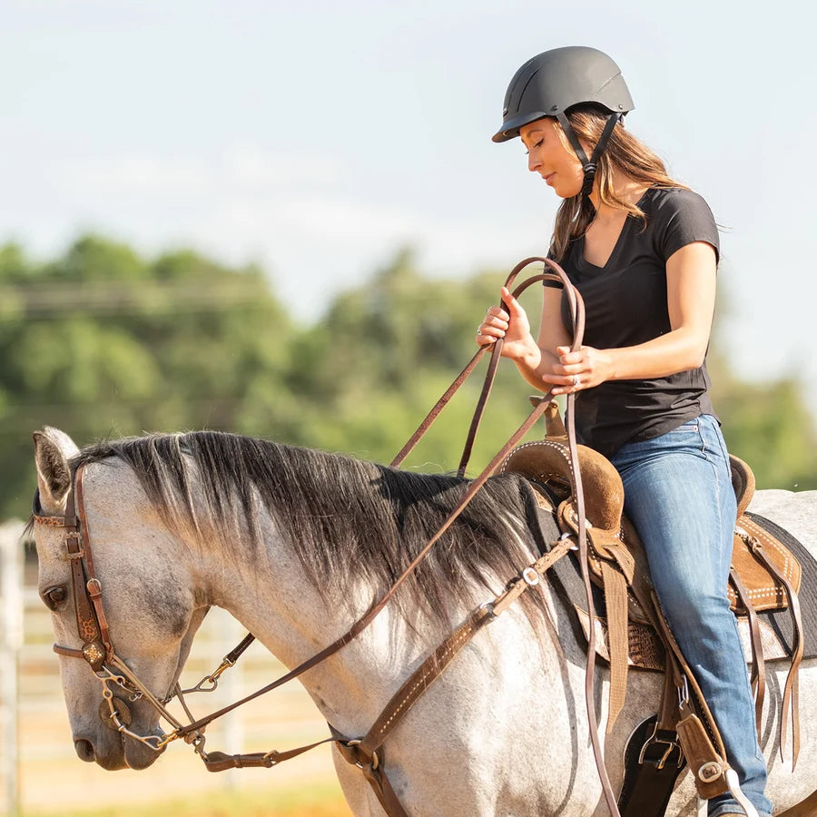 Amazona con casco Troxel Spirit negro caminando junto a un caballo tordo