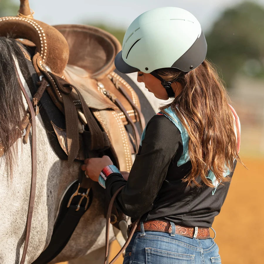 Amazona con casco Troxel Spirit menta Duratec junto a un caballo alazán