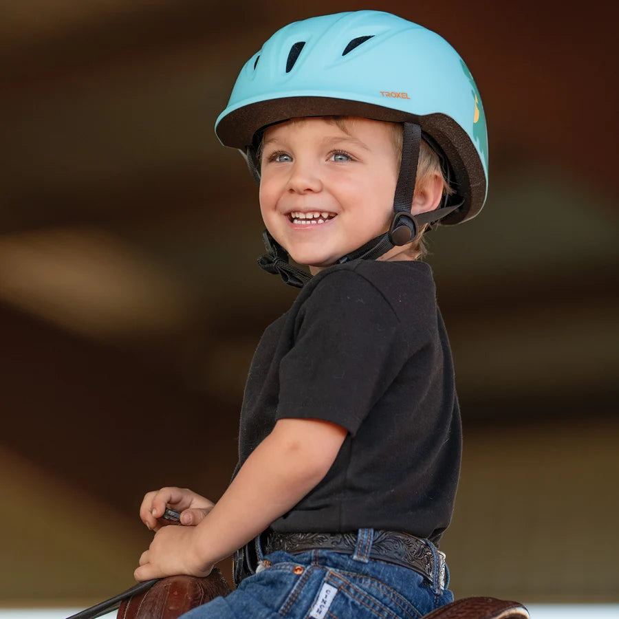 Niño sonriendo con casco Troxel Youngster verde azulado montando a caballo