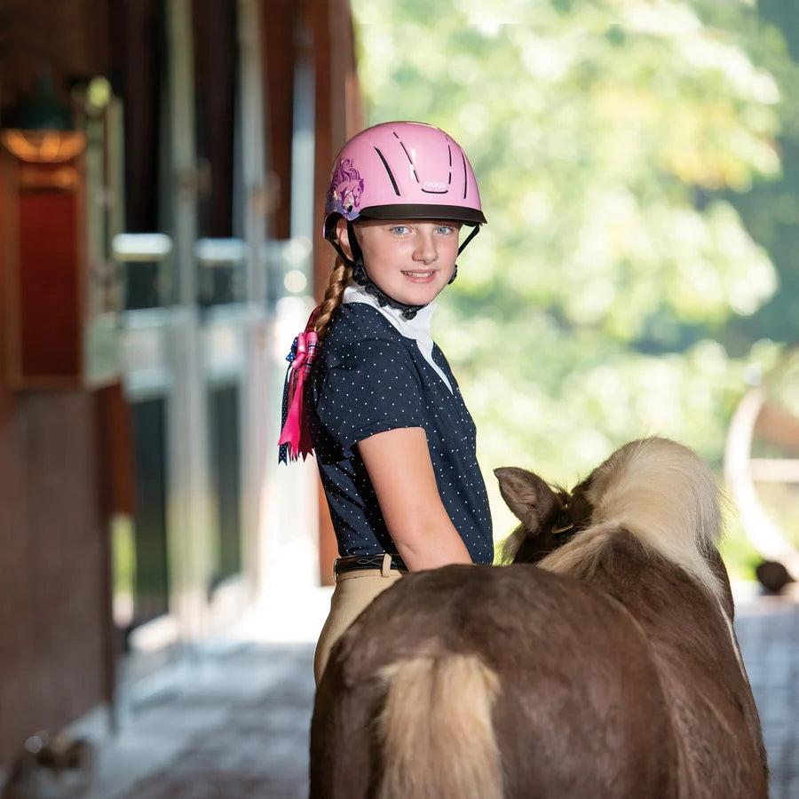 Niña con casco Troxel Spirit Skydream rosa montando a caballo en el establo