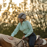 Amazona con camisa verde menta y casco Troxel Spirit MIPS ajustando la silla
