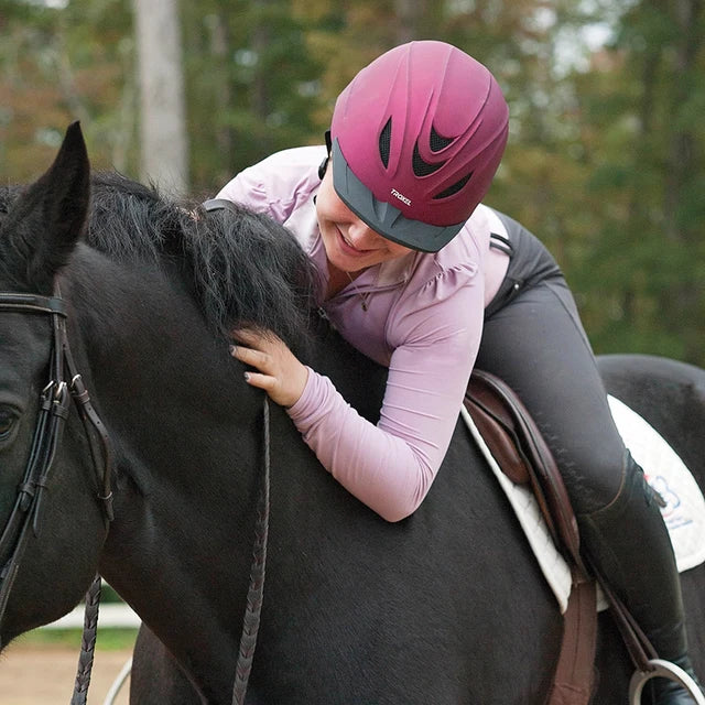 Amazona con casco Troxel Intrepid vino abrazando a un caballo negro