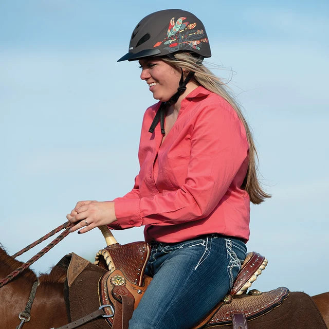 Amazona con camisa coral y casco Troxel Rebel Arrow montando a caballo