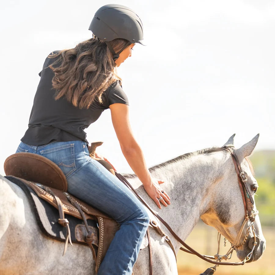 Amazona de espaldas con casco Troxel Spirit negro montando a caballo
