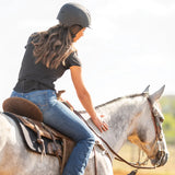 Amazona de espaldas con casco Troxel Spirit negro montando a caballo