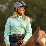 Amazona con camisa verde menta y casco Troxel Spirit MIPS junto a un caballo palomino