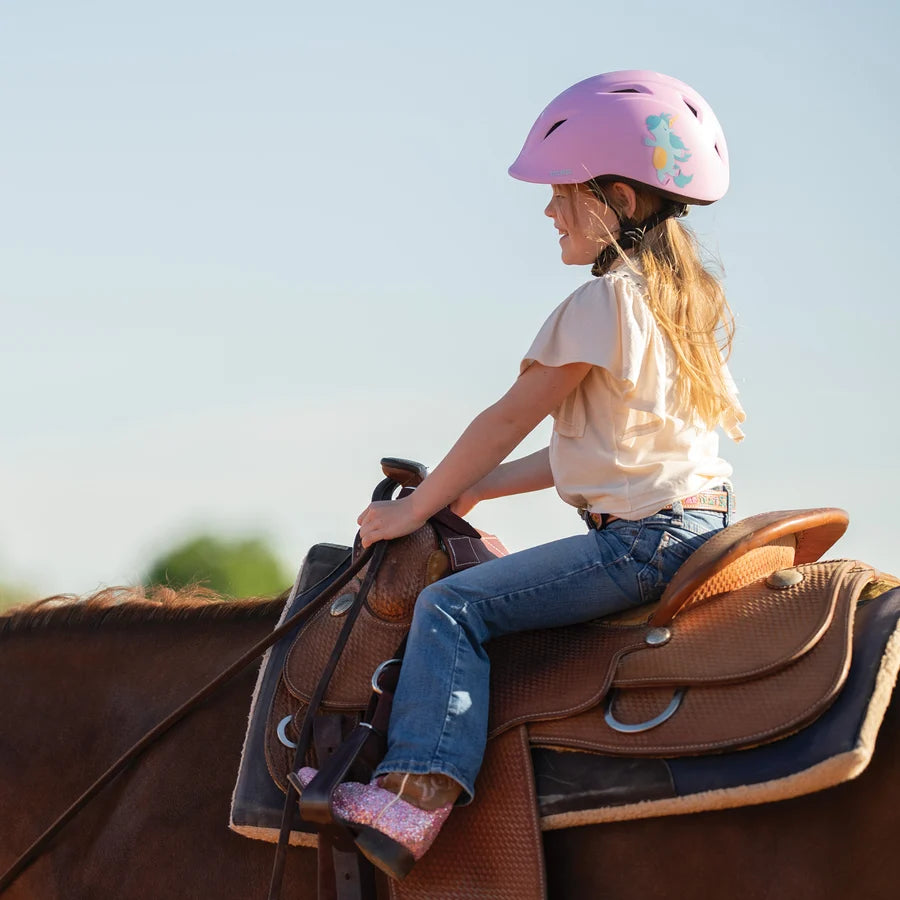 Niña con casco Troxel Youngster lila montando a caballo, vista de espaldas