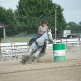 Amazona con casco Troxel Liberty negro montando un caballo tordo en la arena