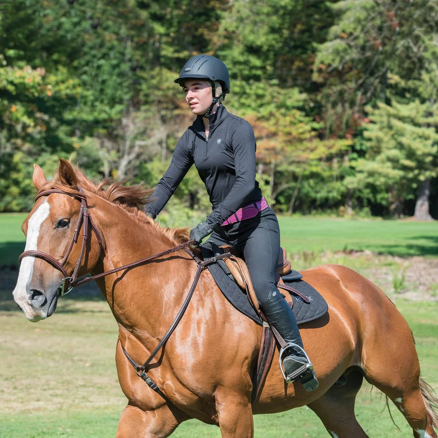 Jinete con casco Troxel Spirit negro montando un caballo alazán en el campo
