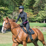 Jinete con casco Troxel Spirit negro montando un caballo alazán en el campo