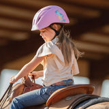 Niña con casco Troxel Youngster lila junto a un caballo