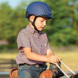 Niño con camisa de cuadros y casco Troxel Spirit azul marino montando a caballo