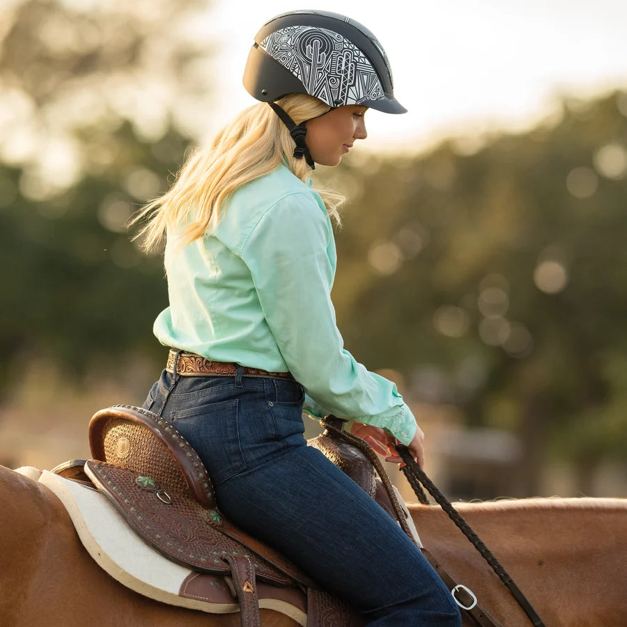 Amazona con camisa verde menta y casco Troxel Spirit MIPS montando a caballo
