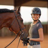 Amazona con casco Troxel Liberty negro acariciando a un caballo alazán
