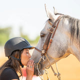 Amazona con casco Troxel Spirit negro acariciando a un caballo tordo